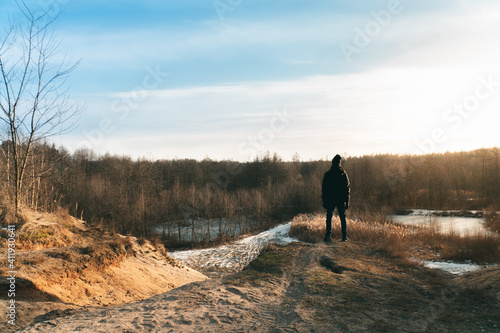 Young man enjoying the sunset and views in the polish countryside, snow melting at the arrival of spring. Around Głuchów in the Mazowieckie region south of Warsaw.