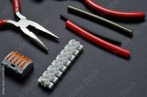 tools for working with electricity, terminal blocks and heat shrink tubes lie on a dark background.