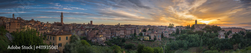 Panorama of Siena old town at sunrise, a medieval and Renaissance city in Tuscany, Italy, with Mangia tower, church, old houses and palaces on a green hill