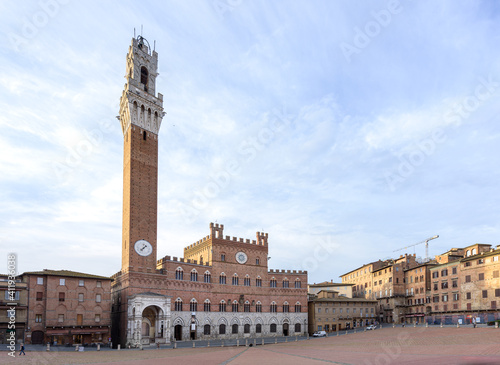 Torre del Mangia, a Renaissance tower and palace are lit by sunrise light in piazza del Campo in Siena, famous for the Palio street horse race, in Tuscany region of Italy.