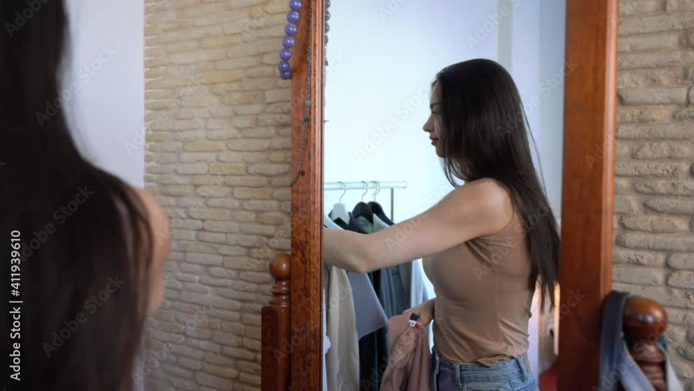 Attractive young woman is Looking in a wardrobe what to wear. Girl upset that there is nothing to wear & taking off her jacket Attractive young woman is Looking in a wardrobe what to wear. Girl upset that there is nothing to wear & taking off her jacket