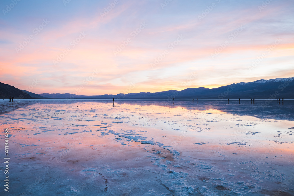 Colorful sunset with mountain reflections at Badwater salt flats. Rainy day at Death Valley National Park, California