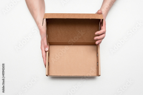 Empty cardboard box with copy space in the male hands on the gray background. © Natali