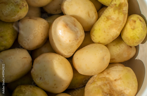 Young peeled potatoes lie in a pot of water. View from above