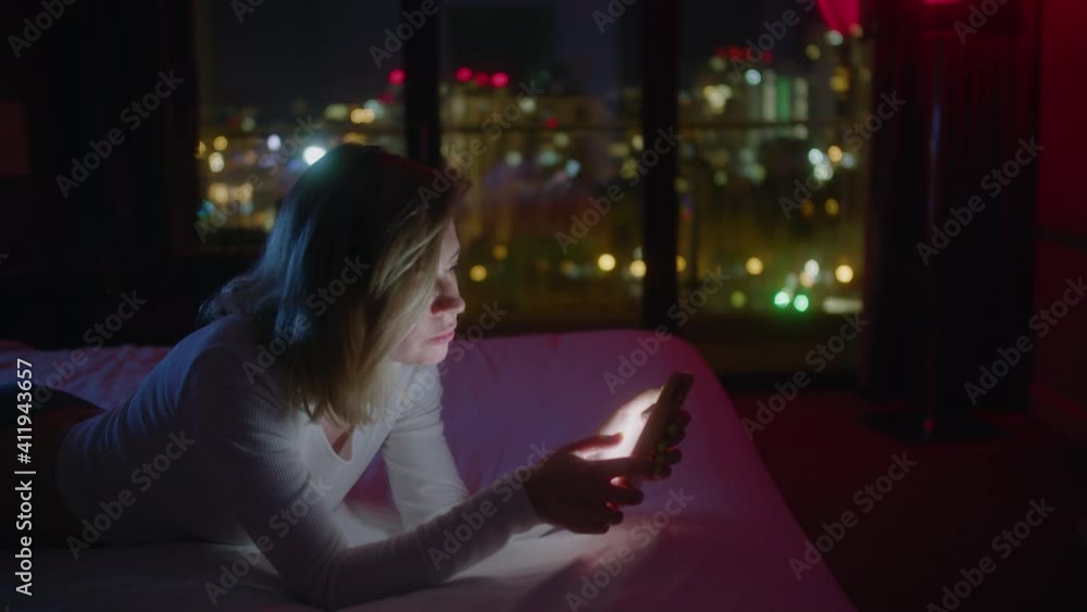 portrait of a young girl in the light of the smartphone screen. girl uses a mobile phone against the background of the night city portrait of a young girl in the light of the smartphone screen. girl uses a mobile phone against the background of the night city