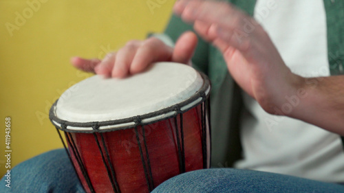 Male hands tapping djembe, bongo in rhythm. Musical handmade instruments