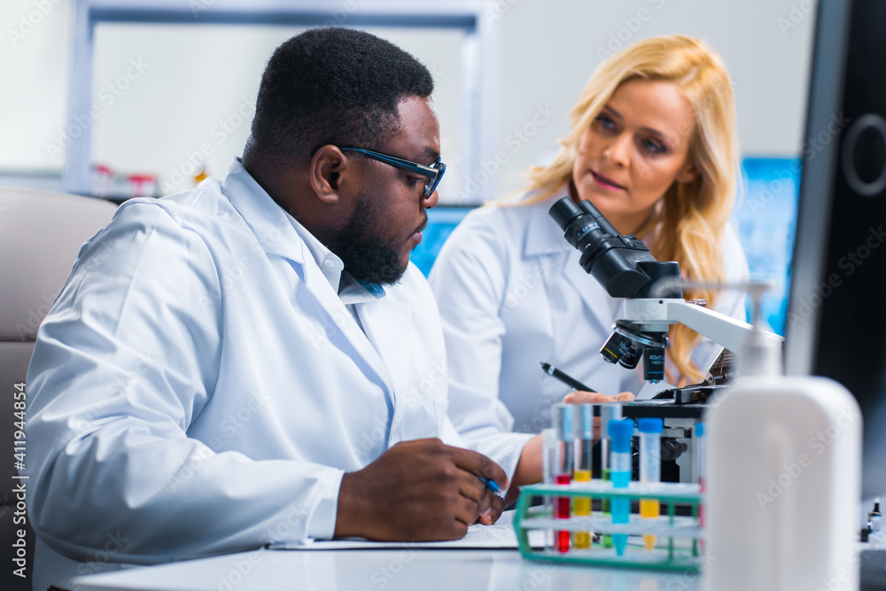 Professional team of scientists is working on a vaccine in a modern scientific research laboratory. Genetic engineer workplace. Future technology and science. Professional team of scientists is working on a vaccine in a modern scientific research laboratory. Genetic engineer workplace. Future technology and science.