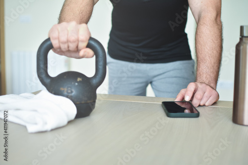 Personal trainer men hanging a phone for a lesson at home