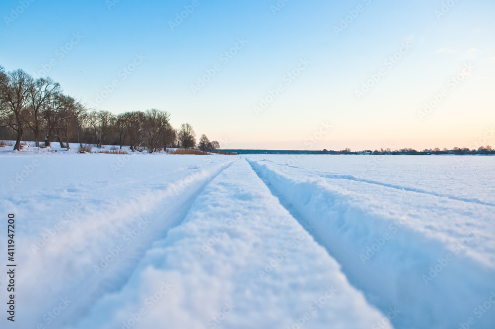 ski track in the snow. in the photo-a ski track on white snow, in a large snow-covered field, close-up, in the background the evening sky ski track in the snow. in the photo-a ski track on white snow, in a large snow-covered field, close-up, in the background the evening sky