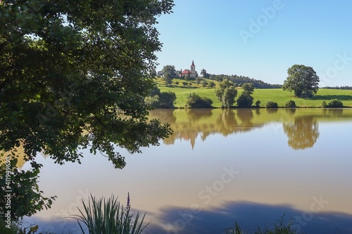 pond with a church on a hill 