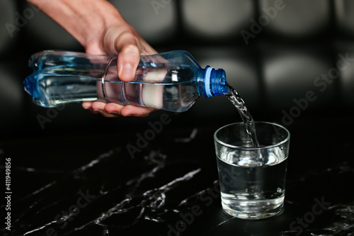 pouring water into a glass. blue bottle with water. water pours from a bottle into a glass on black background