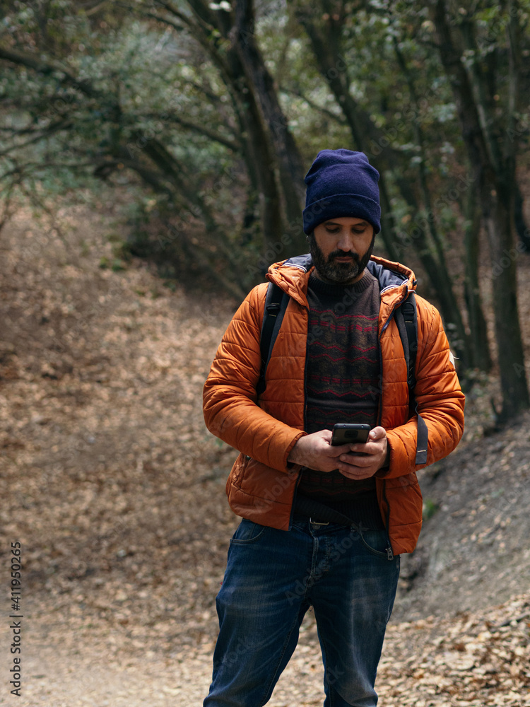Hiker man with beard looking at smart phone