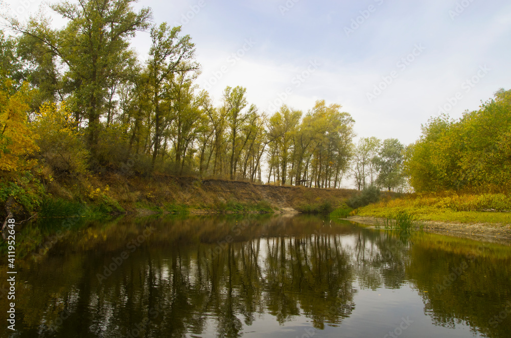 Autumn river landscape with reflection of trees in water
