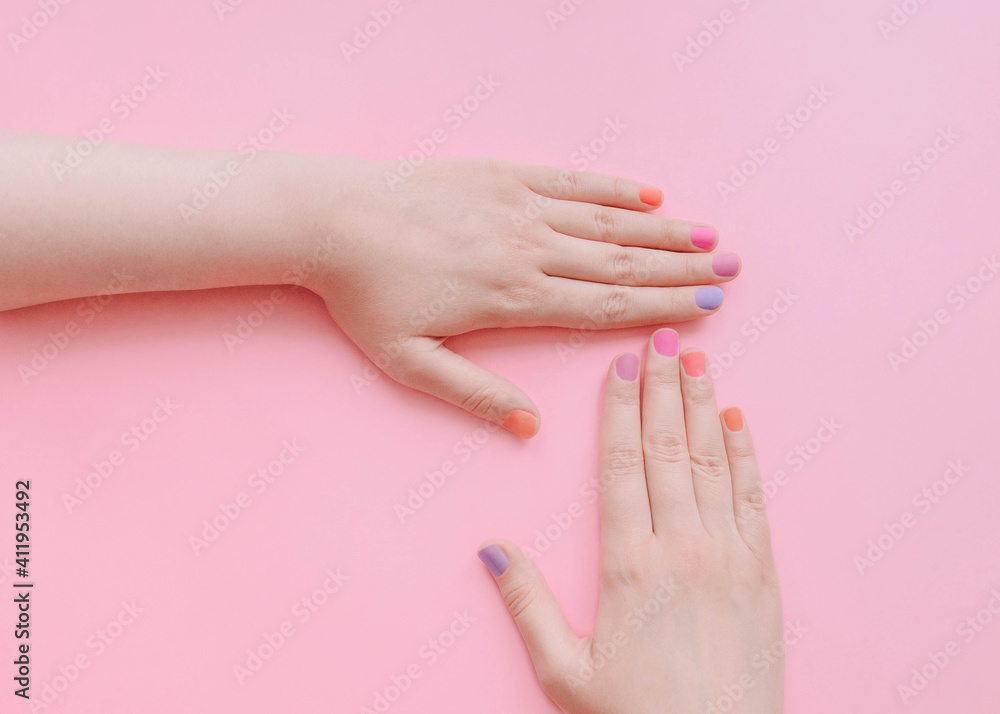 Colored manicure Top view photo with copy space Female hands with multicolored nails on light pink background