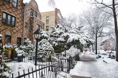 Winter scene with snow covered cars parked along streets in Brooklyn, NY. Brownstones in winter season