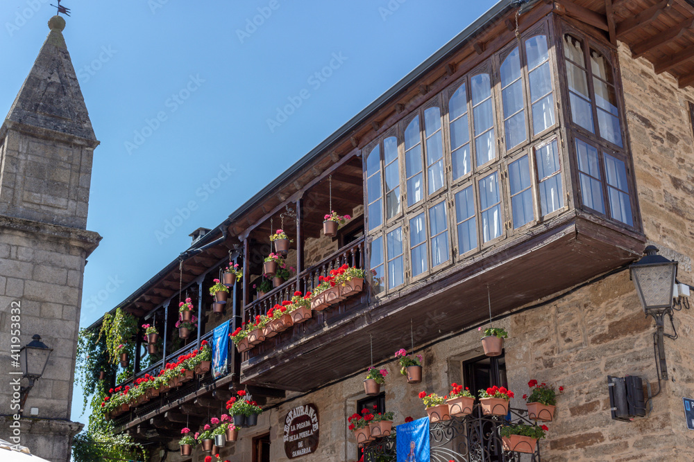 Puebla de Sanabria, Spain - September 6, 2020: Cobblestone street with picturesque stone residential buildings and flowered balconies in Puebla de Sanabría, Zamora province, Castilla y León.