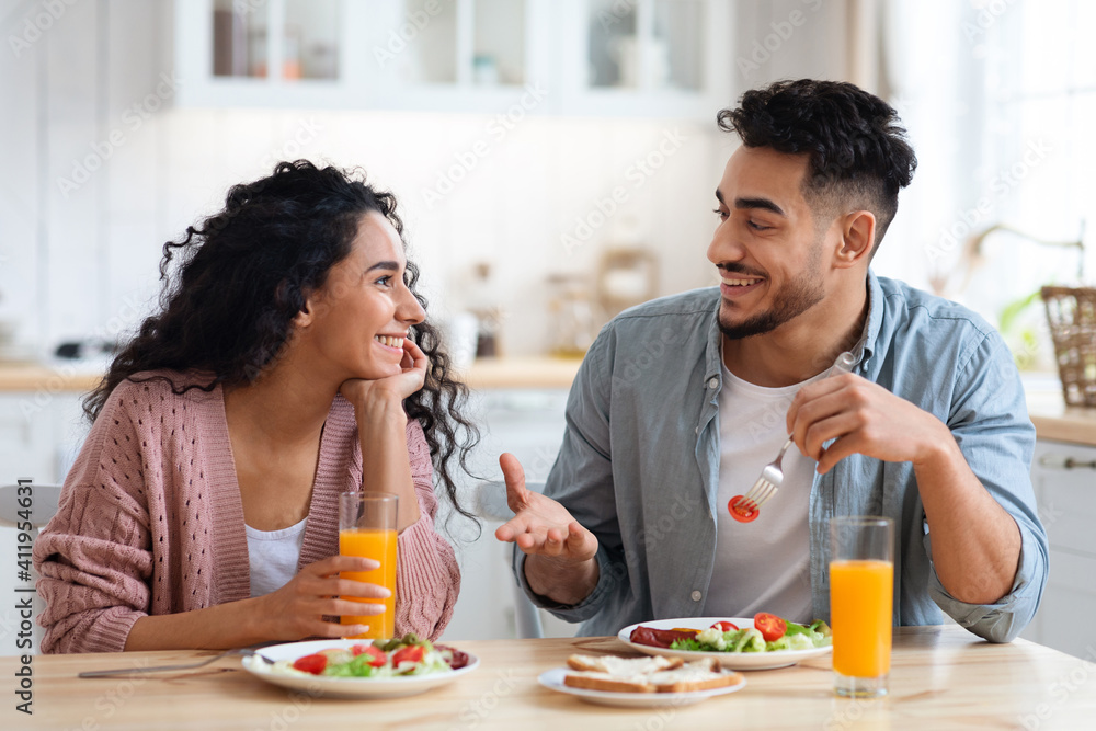 Romantic millennial arab couple eating tasty breakfast together in kitchen at home Romantic millennial arab couple eating tasty breakfast together in kitchen at home
