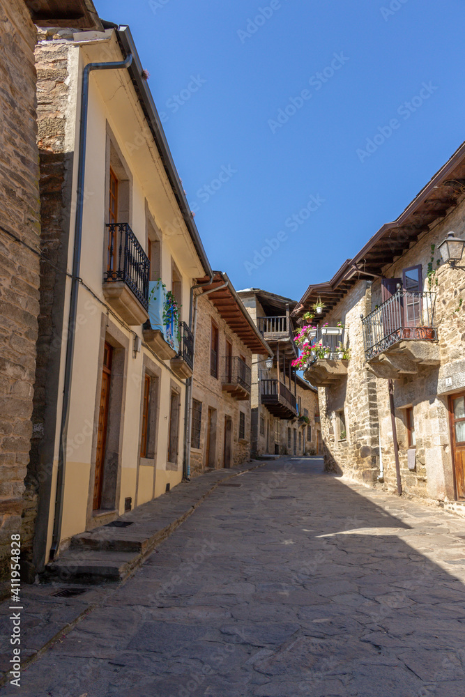 Puebla de Sanabria, Spain - September 6, 2020: Cobblestone street with picturesque stone residential buildings and flowered balconies in Puebla de Sanabría, Zamora province, Castilla y León.
