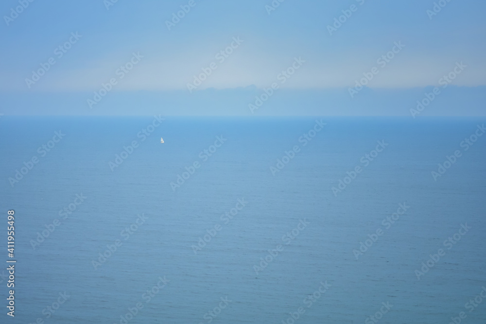 landscape with a blue sea and a sailboat is visible in the distance