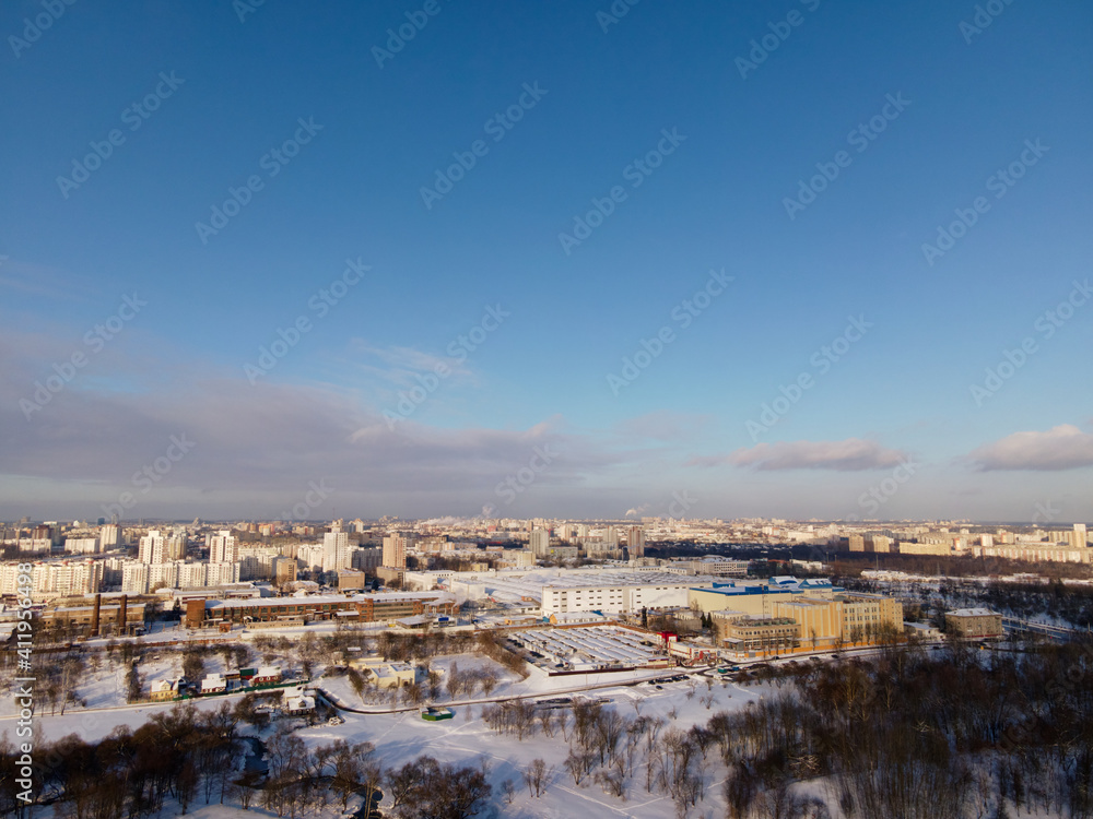 Fototapeta premium Urban winter landscape from above. Multi-storey buildings and trees in the city park are visible.