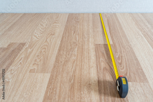 Measuring Wooden Floor with Yellow Measure Tape, Abstract Background