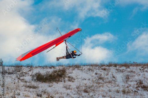 Hang glider pilot flies low above training slope.