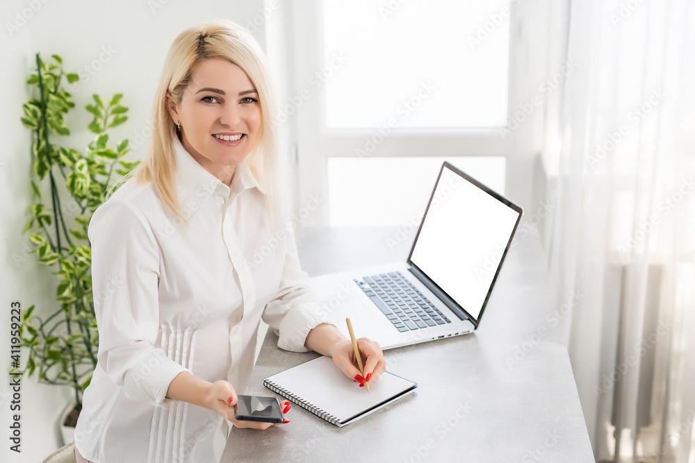 Young woman with laptop writes in notepad Young woman with laptop writes in notepad