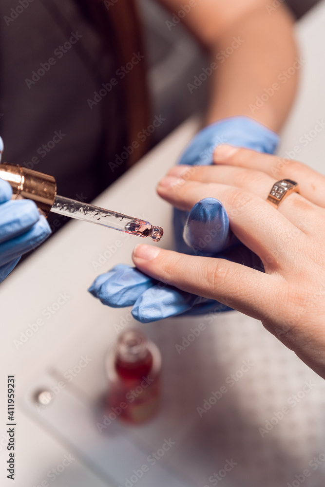 A manicurist applies cuticle oil to men's hands after a hardware manicure in a beauty salon. Apply oil to cuticles. Men's hands care. Manicurist.
