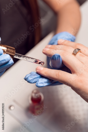 A manicurist applies cuticle oil to men s hands after a hardware manicure in a beauty salon. Apply oil to cuticles. Men s hands care. Manicurist.