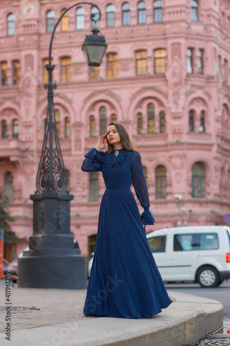 Elegant caucasian woman with long straight brunette hair in blue and white stylish colorful dress walking city street on a bright day © Dmitry Tsvetkov