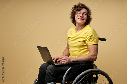 Foto disabled man sits in a wheelchair with laptop, working online