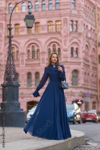 Elegant caucasian woman with long straight brunette hair in blue and white stylish colorful dress walking city street on a bright day © Dmitry Tsvetkov