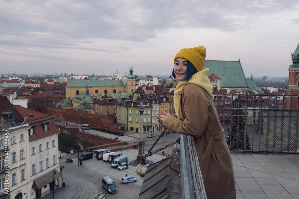 Happy young woman portrait with colored blue hair in coat in front of old town and Christmas tree