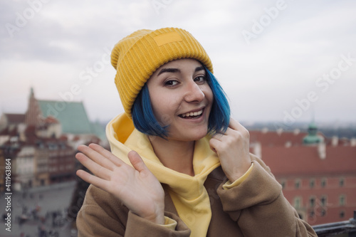 Happy young woman portrait with colored blue hair in coat in front of old town and Christmas tree photo