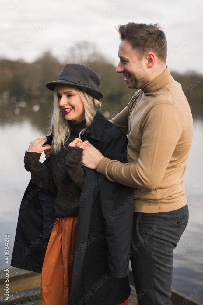 Gentleman covering his girlfriend with a jacket a cold autumn day on a pier Gentleman covering his girlfriend with a jacket a cold autumn day on a pier