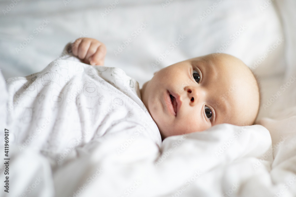 Adorable baby boy in white bedroom. Newborn child relaxing in bed. Nursery for young children. Textile and bedding for kids. Family morning at home. lifestyle concept, real life. Adorable baby boy in white bedroom. Newborn child relaxing in bed. Nursery for young children. Textile and bedding for kids. Family morning at home. lifestyle concept, real life.
