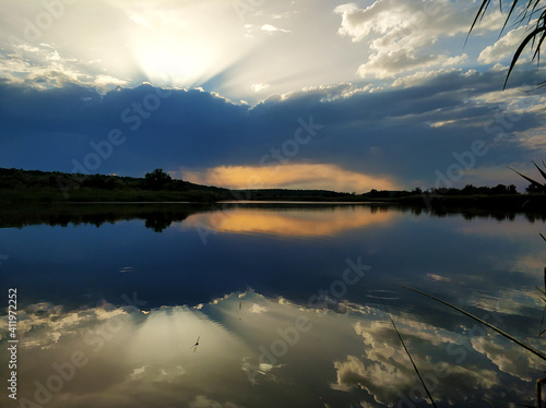 Fototapeta Naklejka Na Ścianę i Meble -  Natural landscape. Sunset over water, reflection of the sun and clouds in the water