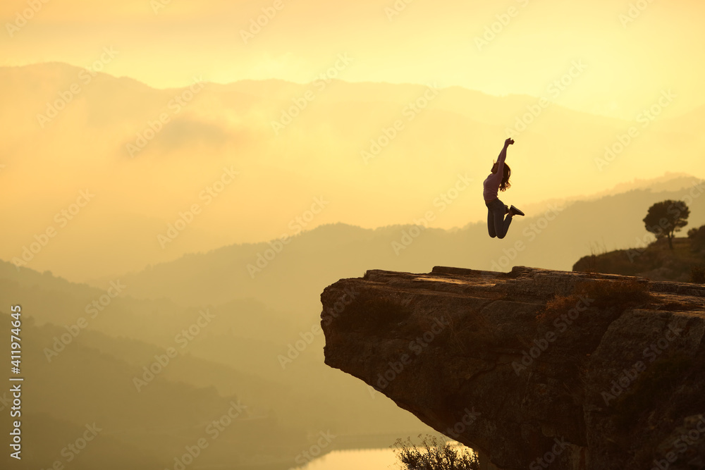 Woman jumping in a cliff in the mountain