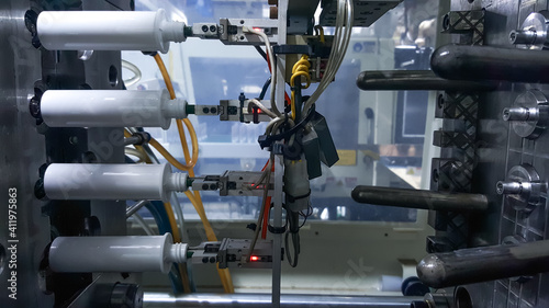 Robot arm holding plastic bottles, on the background of injection molding machines, in the working line of the plastics factory. photo