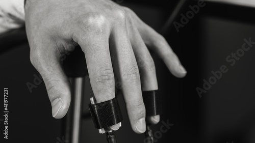 black and white photo, close up, on men's hands wearing polygraph sensors, truth detector for polygraph transmission, side view. Selective focus.