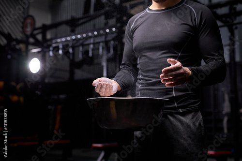 athlete man getting ready for weight lifting training, using talc, preparing hands for workout. at gym. sport and bodybuilding concept