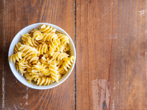 Top view of fusilli giganti in bowl on wood table with space for letters. High resolution