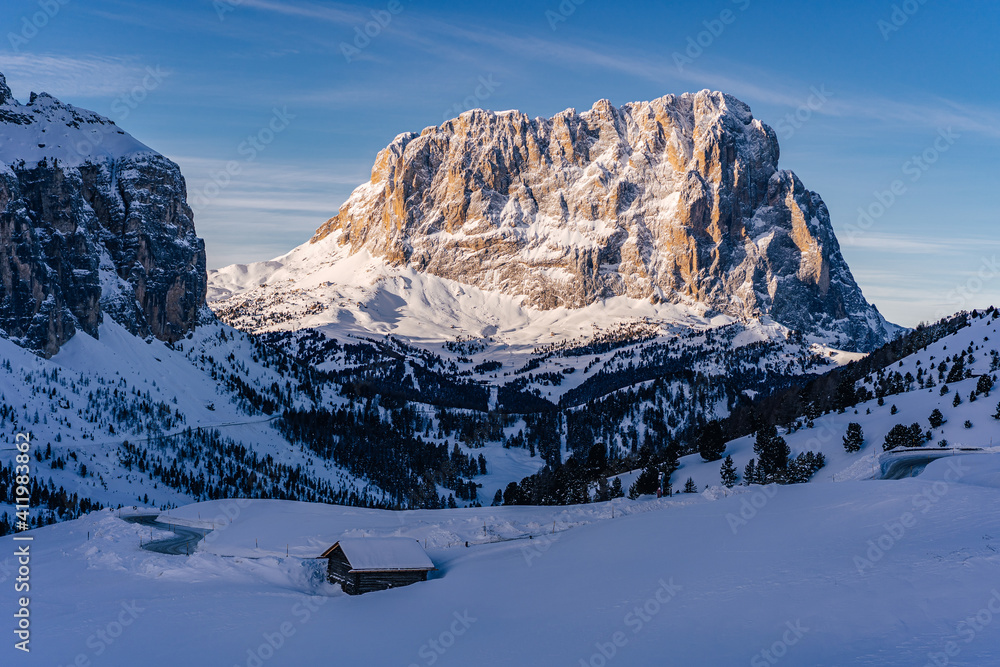 View of a winter mountain landscape of Dolomites, Italy. Sassolungo mountain in morning sunrise light. Langkofel mountain with snow from Passo Gardena, South Tyrol.