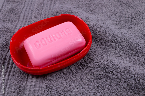 gray towel, and on it lies a red soap dish and pink soap in it