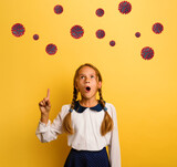 Young student is with shocked expression and indicates codiv-19 virus. Yellow background