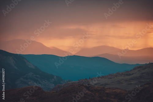 Atmospheric landscape with silhouettes of mountains with trees on background of orange dawn sky. Colorful nature scenery with sunset or sunrise. Sundown paysage in vintage colors and faded tones. © Daniil