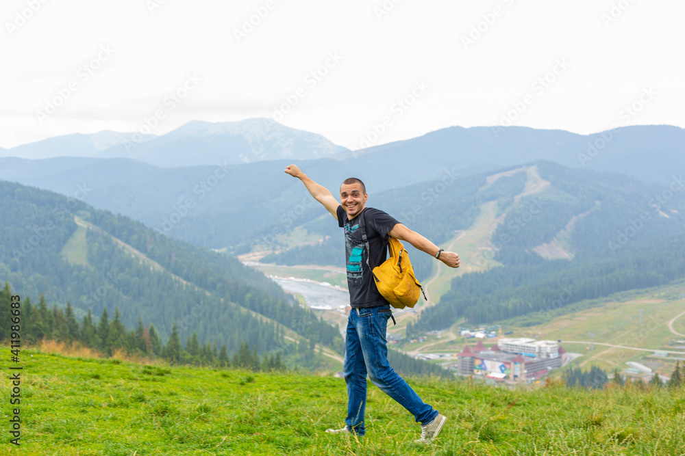 A guy travels with a yellow backpack through picturesque places with beautiful mountain landscapes A guy travels with a yellow backpack through picturesque places with beautiful mountain landscapes