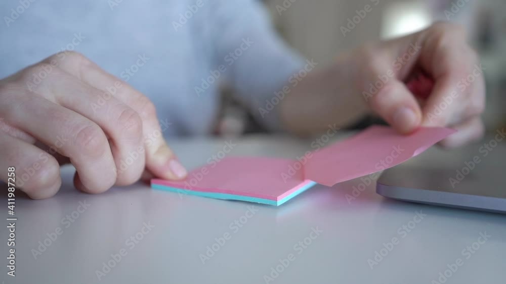 Young Woman Writing Important Notes On Stickers At Table In Office and Sticking it On Computer Young Woman Writing Important Notes On Stickers At Table In Office and Sticking it On Computer