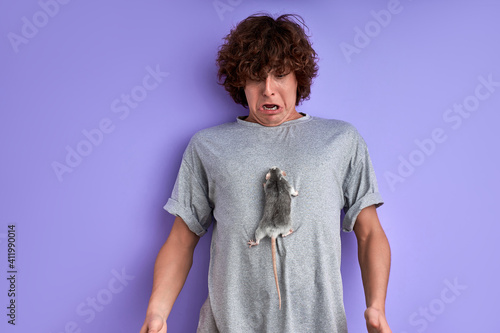 male with rat climbing up on his t-shirt, man is in shock by it's activity, crawling rat photo