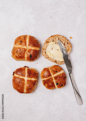 Traditional English Easter Hot Cross Buns with butter and knife on grey background, top view